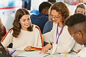 Female teacher helping student with homework in classroom