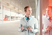 Young man with tablet and headphones waiting