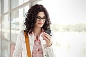 Young woman using smart phone at window