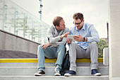 Businessmen talking, using digital tablet on steps