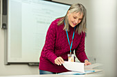 Smiling instructor with paperwork preparing in classroom