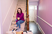 Woman redecorating, looking at paint swatch on stairs