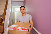 Portrait happy man carrying moving box in corridor