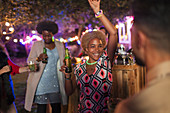 Carefree woman dancing and drinking at garden party