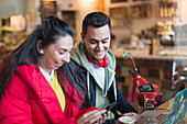 Young couple using smart phone and laptop in cafe