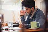 Focused young male college student studying in cafe