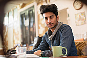 Portrait young male college student studying in cafe