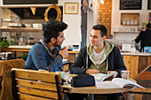 Young male college students studying and talking in cafe
