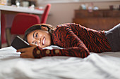 Smiling teenage girl using smart phone on bed