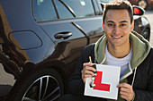 Portrait confident, man holding learners permit by car