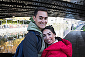 Portrait happy young couple hugging along canal