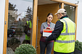 Woman signing for package from deliveryman at front door