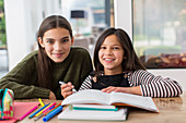 Portrait happy sisters colouring, doing homework