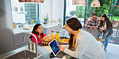Family talking, using digital tablets in kitchen