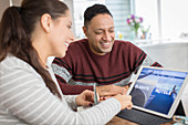 Happy couple planning vacation at digital tablet