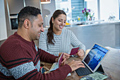 Happy couple with passports planning vacation at tablet