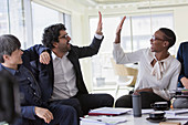 Business people high-fiving in conference room meeting