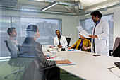 Male doctor leading conference room meeting