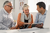 Doctor with tablet meeting with couple in doctors office