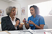 Doctor teaching diabetic patient how to use glucometer