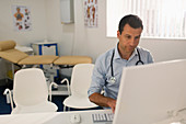 Male doctor working at computer in doctors office