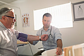 Male doctor checking blood pressure of senior patient