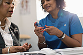 Doctor teaching diabetic patient how to use glucometer