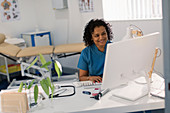 Female doctor working at computer in doctors office