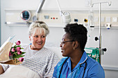 Female patient showing flowers to nurse in hospital room