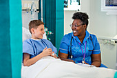 Female nurse talking with boy patient in hospital room