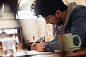 Focused young male college student studying in cafe