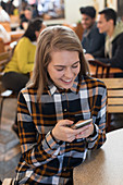 Young woman using smart phone in cafe