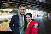 Portrait happy young couple hugging along canal