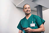 Smiling male surgeon using smart phone