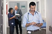 Male doctor using digital tablet in hospital corridor