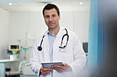 Portrait male doctor using digital tablet in hospital room