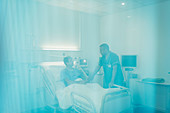 Male nurse talking with patient in hospital room