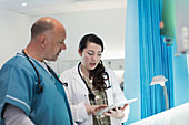 Doctors with digital tablet talking in hospital room