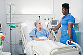 Female nurse talking with patient in in hospital room