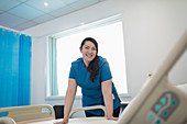 Portrait confident, female nurse making hospital bed