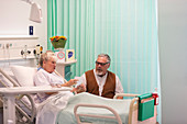 Senior man visiting wife resting in hospital room