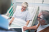 Affectionate man talking with wife resting in hospital bed