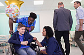 Doctor and nurse talking with boy patient in wheelchair