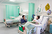 Man visiting, talking with wife resting in hospital ward
