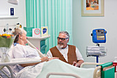 Affectionate man visiting, talking with wife resting