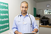 Male doctor with digital tablet in hospital corridor