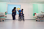 Doctor and nurse pushing boy patient in wheelchair