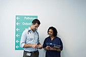 Doctors with smart phones talking in hospital corridor