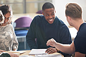 Happy college students studying and talking in classroom