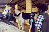 Instructor helping girls prepare for horseback riding